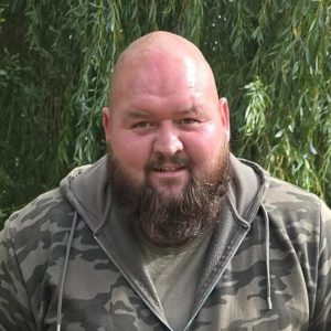 Dillan (owner of Perflection) in a camo jumper with tress behind him