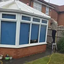 Man cleaning a conservatory roof standing on a small platform