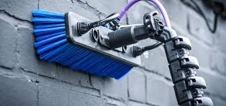 Blue window cleaning brush with purple pipes lent on a grey painted brick wall