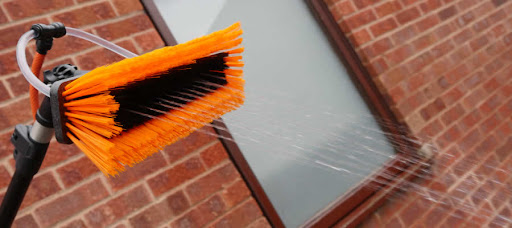 Orange window cleaning brush head spraying water from its jets
